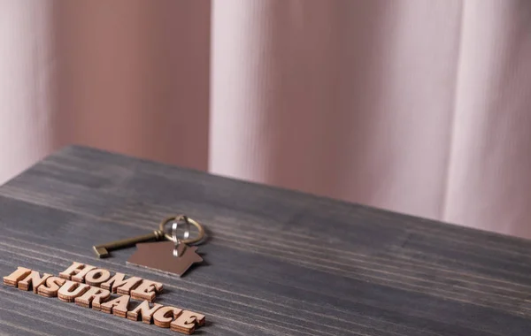 木製のテーブルの上に家の鍵と保険本文をホームします — ストック写真