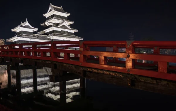 木红色桥梁和松本城堡在晚上 — 图库照片