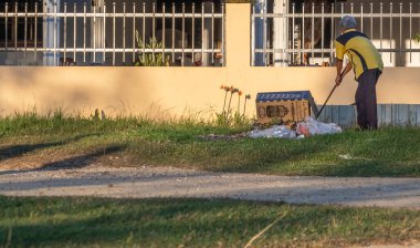 KUALA KANGSAR, PERAK, MALAYSIA - 22 Şubat 2020: Yaşlı Malaylı adam akşam çimlerini temizliyor