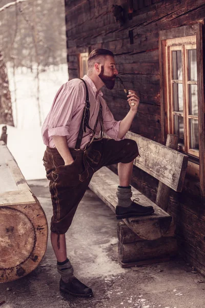 Bavarian Man Lederhosen Enjoys His Pipe Front His Log Cabin — Stock Photo, Image