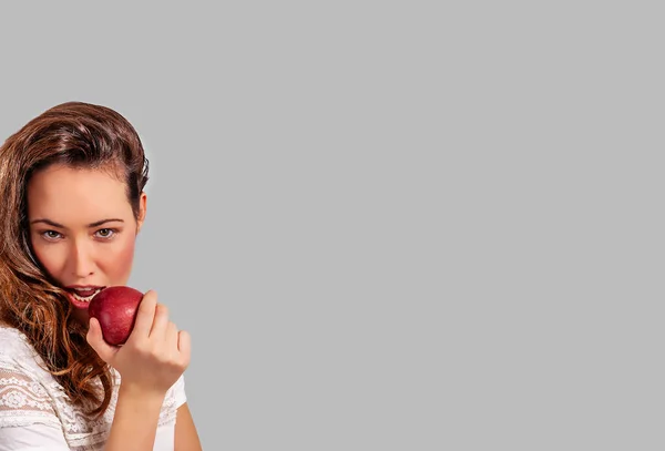 Νεαρή Μελαχρινή Γυναίκα Τρώει Ένα Κόκκινο Μήλο Απομονωμένα Γκρι Μορφή — Φωτογραφία Αρχείου