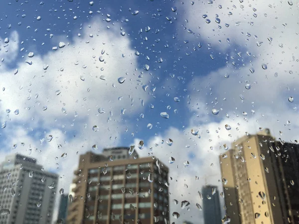Regen druppels op windowpane tegen gebouwen — Stockfoto