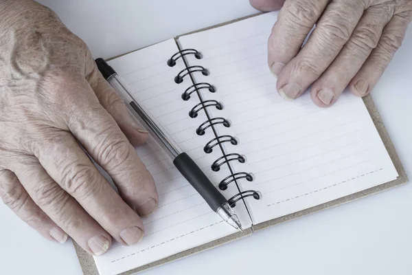 Wrinkled hands on an empty notebook