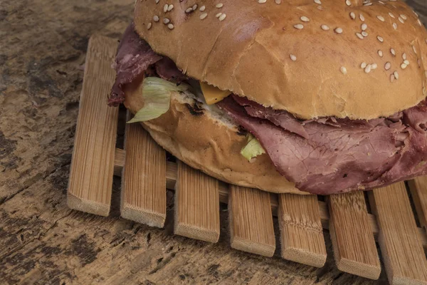 Pečené hovězí burger na dřevěný stůl — Stock fotografie