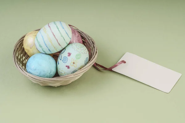 Tekne isimi nakışlı sepet içinde renkli Paskalya yumurtaları — Stok fotoğraf