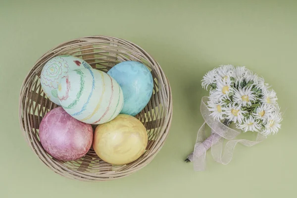Barevné velikonoční vejce v košíku na zelené — Stock fotografie