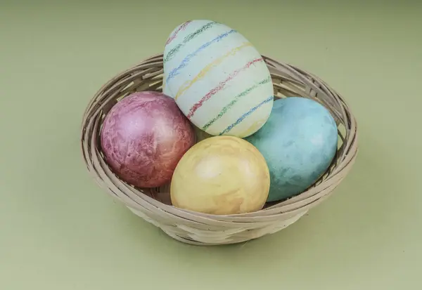 Цветные пасхальные яйца в корзине на зеленом — стоковое фото