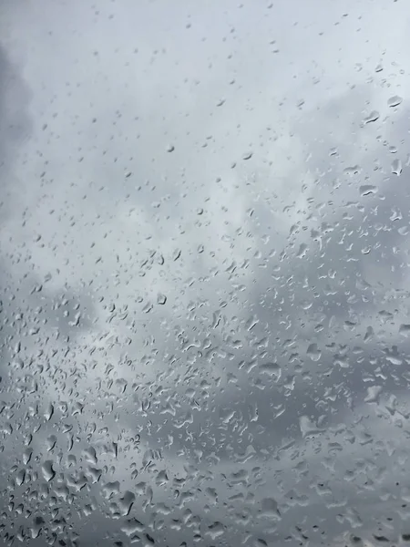 Gocce di pioggia sulla finestra contro il cielo lunatico — Foto Stock