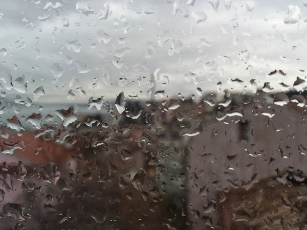 Regentropfen auf Fenster gegen Gebäude — Stockfoto