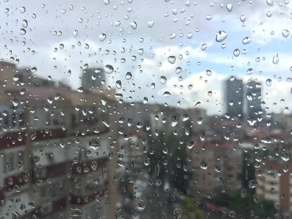 Binalar karşı pencere camı üzerinde yağmur damlaları — Stok fotoğraf
