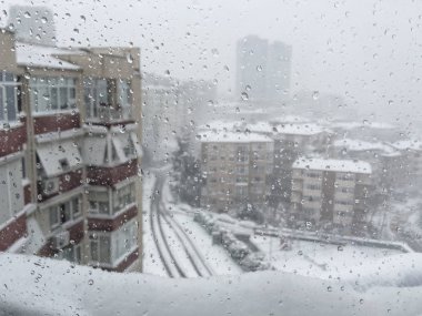 Damla penceresinde şehir görünümü altında karşı kışın kar