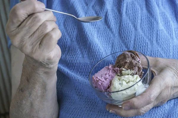 closeup wrinkled hands holding a bowl of ice cream