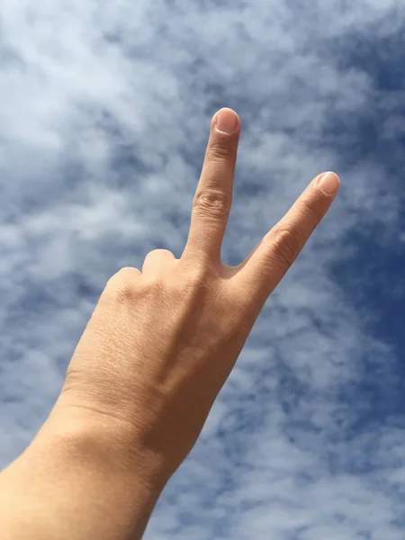 Женская Рука Делает Знак Победы Против Голубого Неба — стоковое фото