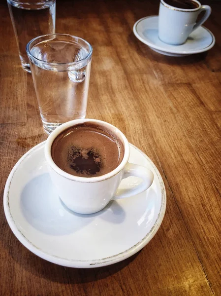 Tazas de café y agua sobre mesa de madera — Foto de Stock