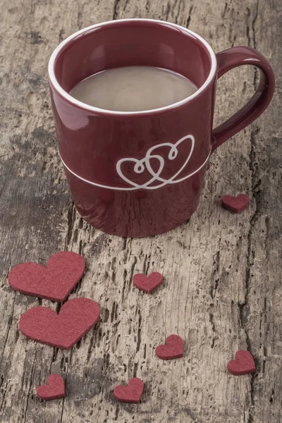 coffee in a red mug decorated with hearts on wooden table for love