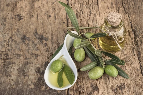 Unripe green olives and olive oil on wooden table