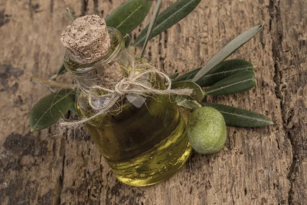 Unripe green olive and olive oil on wooden table