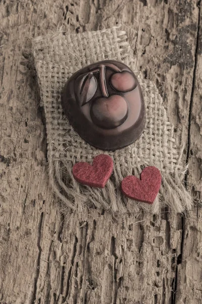 Шоколадная плитка и красные сердца на деревянном столе — стоковое фото