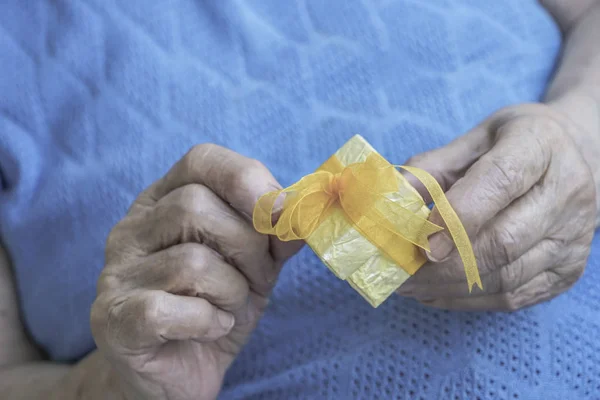 closeup of wrinkled hands holding a gift box