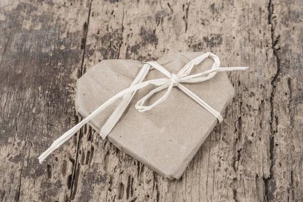 Regalo en forma de corazón sobre fondo de madera — Foto de Stock