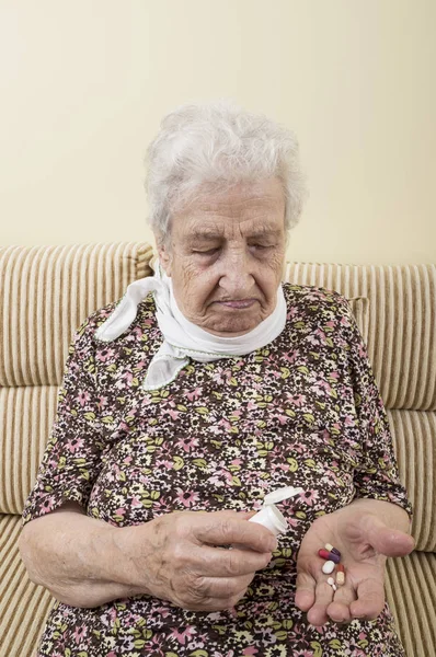 An ill senior woman holding pills on palm