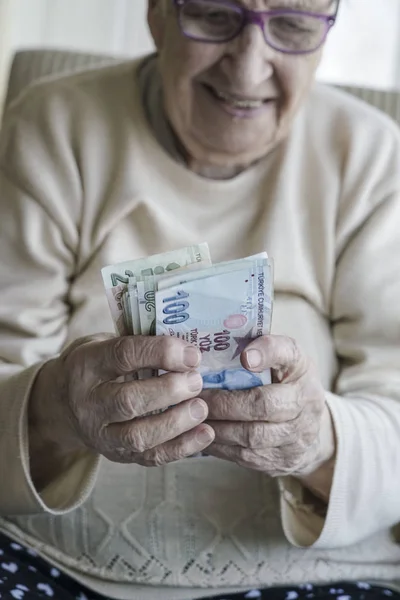 Wrinkled hands of a happy senior woman counting turkish lira banknotes