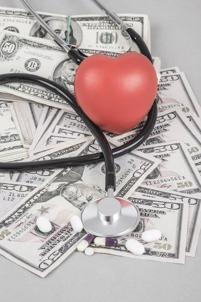 A stethoscope and a red heart on American Dollars on grey background