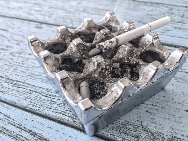 Closeup of cigarette on a silver ashtray — Stock Photo, Image