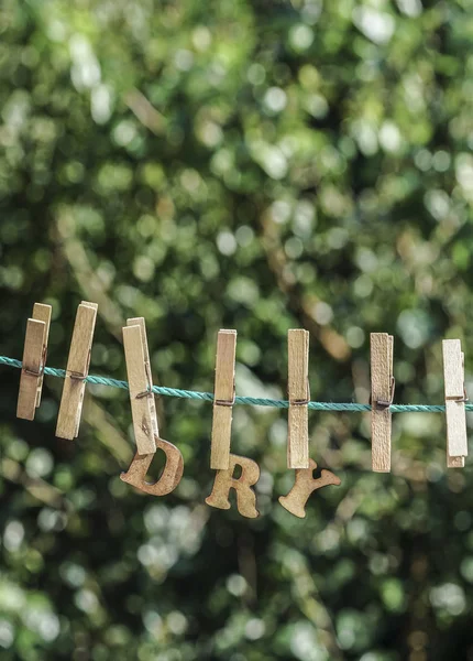 Сухое слово, написанное повешенными деревянными буквами на огороде — стоковое фото