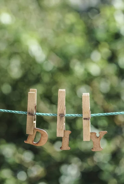 D.I.Y. palabra escrita por letras de madera colgada en la cuerda en el jardín — Foto de Stock