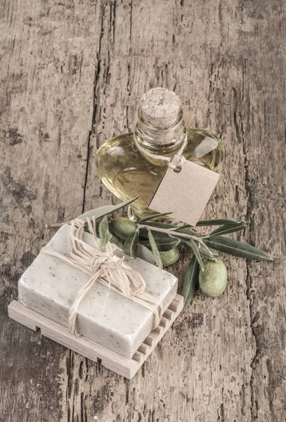 Barra de jabón natural y botella de aceite de oliva en mesa de madera — Foto de Stock