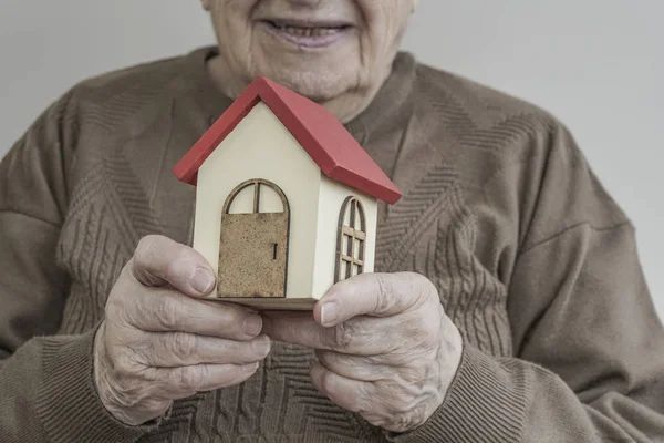 小さな木の家を保持している年配の女性 — ストック写真