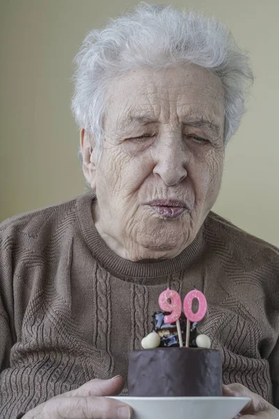 Üst düzey kadın pasta ve onun doğum günü mumu üfleme — Stok fotoğraf