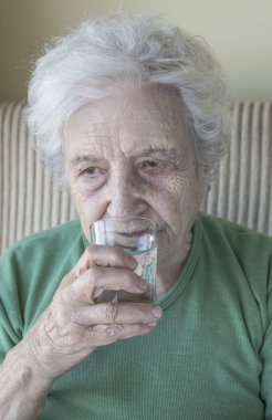Yaşlı kadın su içiyor.