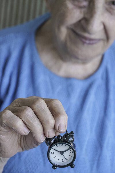 старшая женщина держит часы