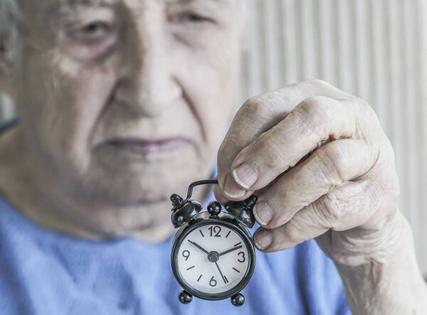 старшая женщина держит часы