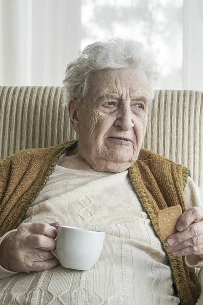 Mujer mayor bebiendo café con galletas — Foto de Stock