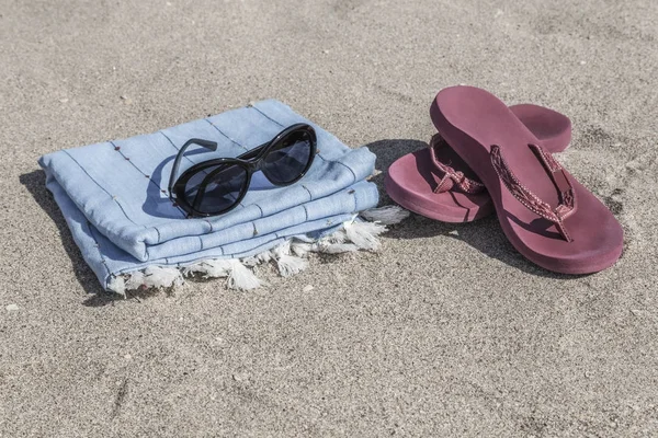 Fondo de verano con chanclas y toalla en la playa — Foto de Stock