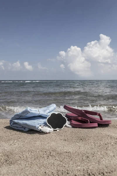 Καλοκαιρινό φόντο με σαγιονάρες και πετσέτα στην παραλία — Φωτογραφία Αρχείου
