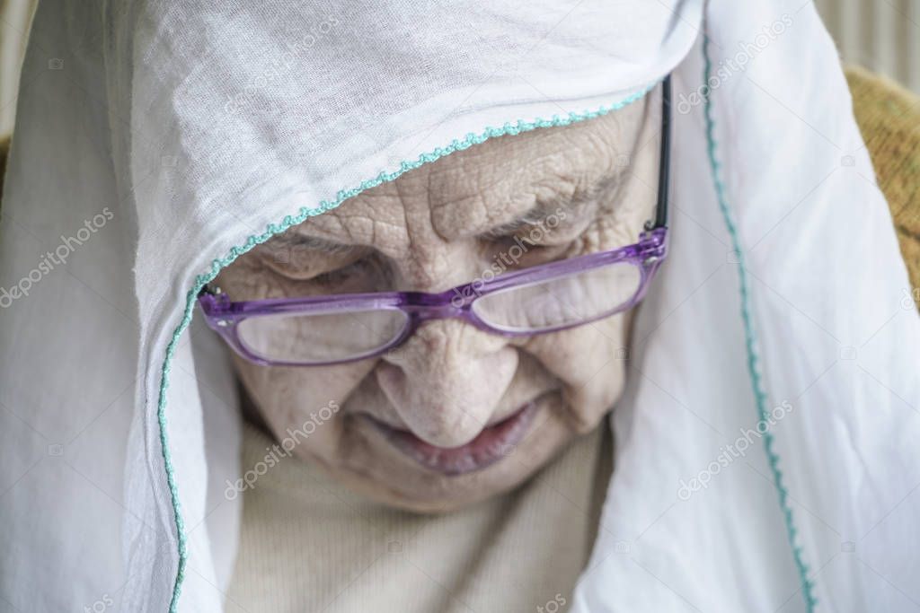 senior woman wearing headscarf while praying