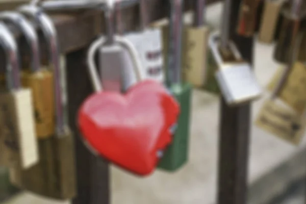 Verschwommener Hintergrund mit Liebessymbol-Vorhängeschlössern an Brücke aufgehängt — Stockfoto