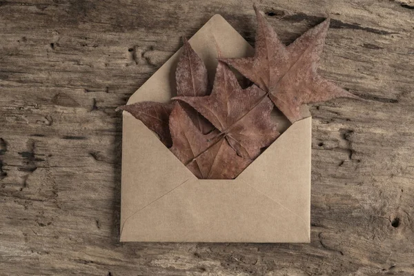 Enveloppe sur une table en bois ornée de feuilles d'automne séchées — Photo