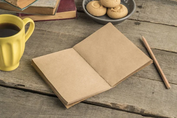 Cuaderno en blanco, café y galletas en una mesa de madera — Foto de Stock