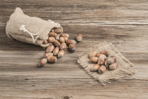Råa hasselnötter i en säckväv på träbordet — Stockfoto