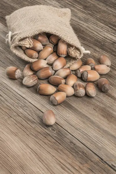 Rauwe hazelnoten in een jute zak op houten tafel — Stockfoto
