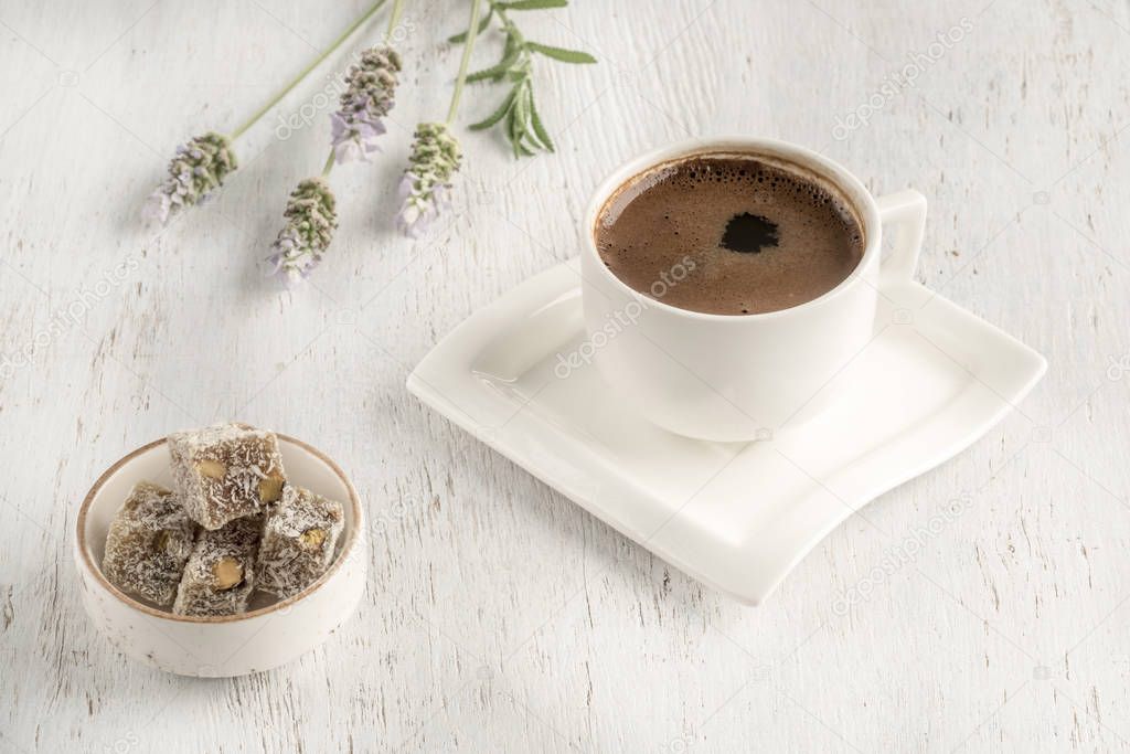 Cup of coffee served with Turkish delight on wooden table
