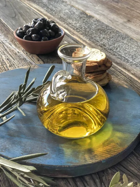 Botella de aceite de oliva y aceitunas sobre una mesa de madera Fotos De Stock