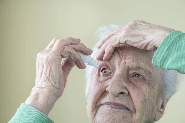 Пожилая женщина, которая сама наносила глазные капли себе в глаза — стоковое фото