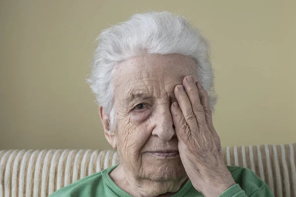 Una mujer mayor su único ojo con su mano arrugada Fotos De Stock