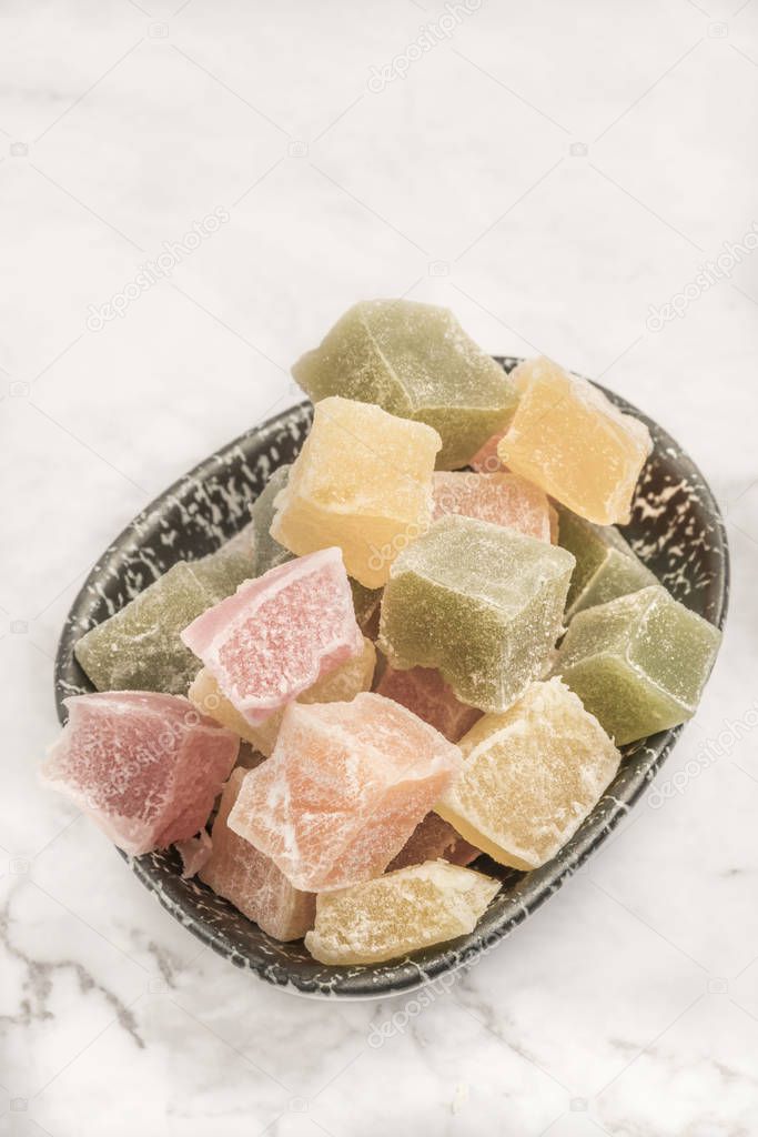 colorful Turkish delights in a bowl on a table with copy space
